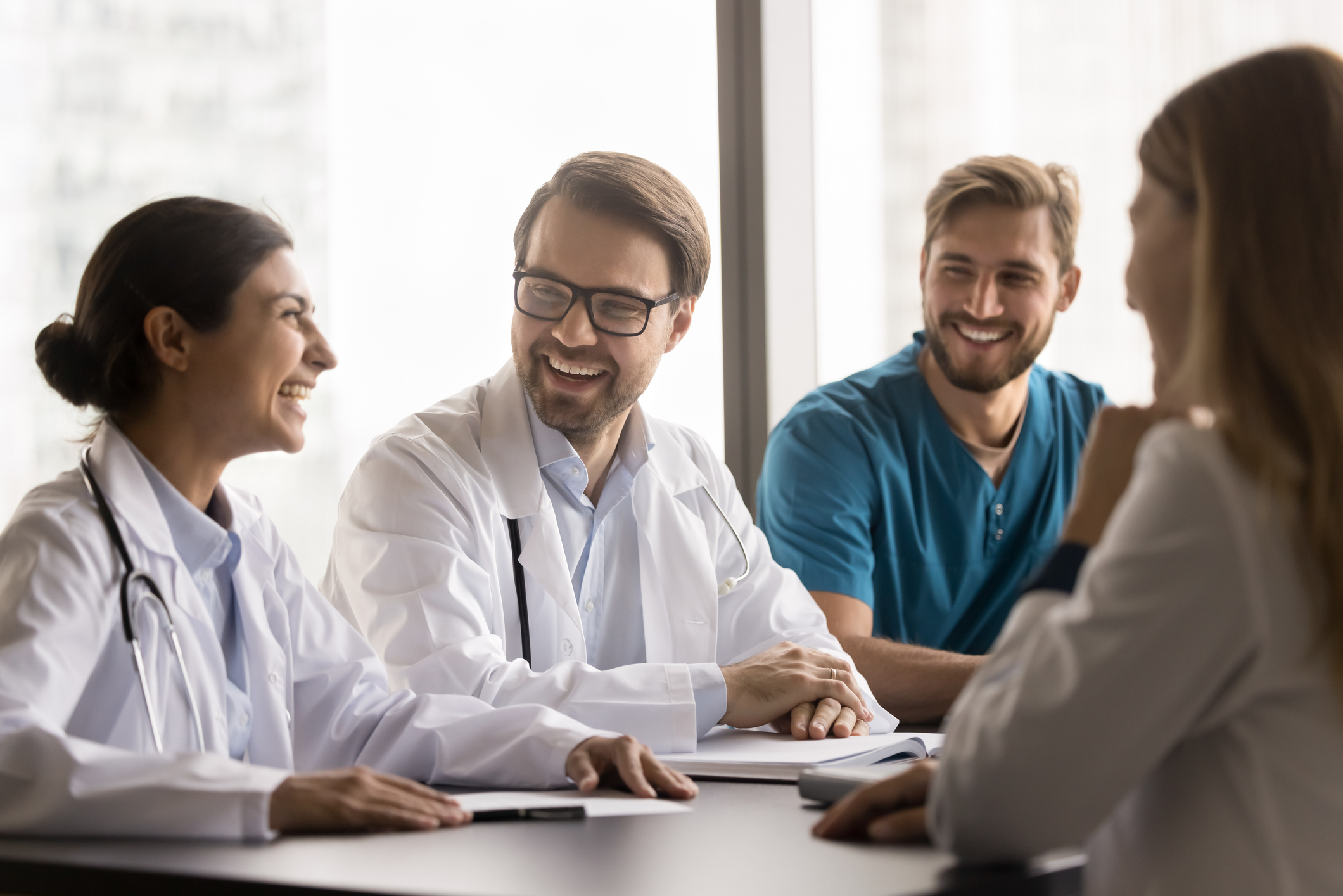 Fun and friendship at work. Young diverse medical staff polyethnic doctors interns engaged in joyful conversation after hospital shift share hilarious professional jokes laugh on funny patient story