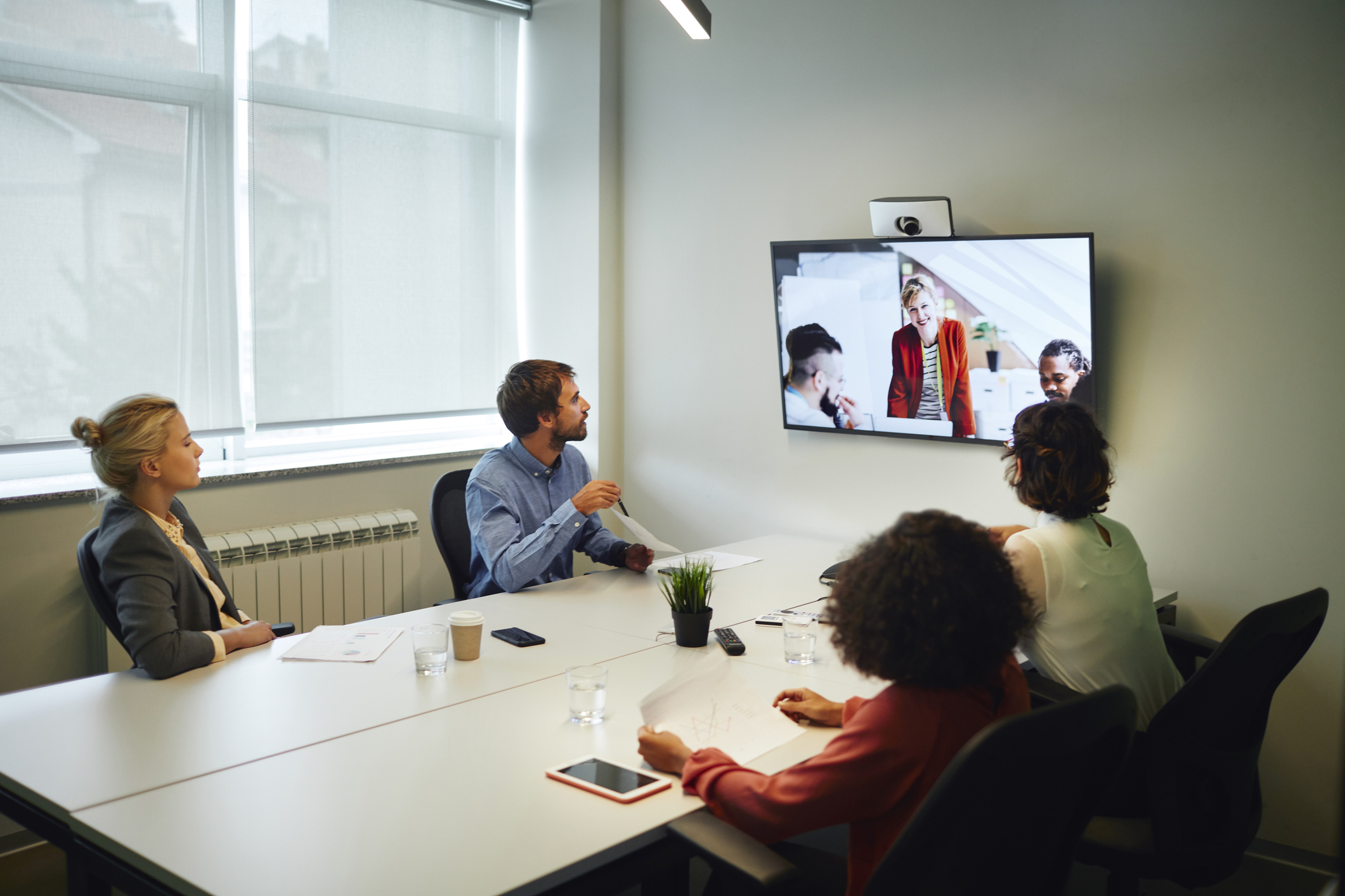 Business People Having a Video Call in Board Room. Sitting by the desk and talking with coworkers on lcd tv.